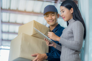 Woman customer signing receipt and receiving the parcel from delivery man. Business and logistic concept.