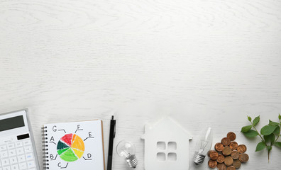 Trendy flat lay composition with energy efficiency rating chart, house figure and coins on white...