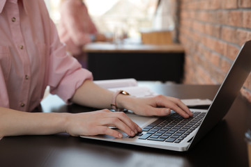 Young businesswoman using laptop at table in office, closeup