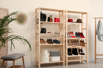 Obraz na płótnie Canvas Wooden shelving unit with different shoes and accessories in stylish room interior