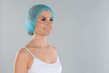 Portrait of woman with marks on face against grey background, space for text. Cosmetic surgery