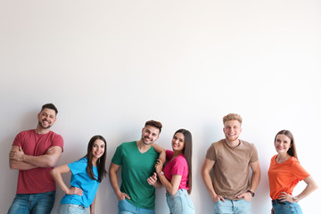 Group of happy people posing near light wall, space for text