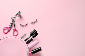 Flat lay composition with false eyelashes and makeup bag on pink background, space for text