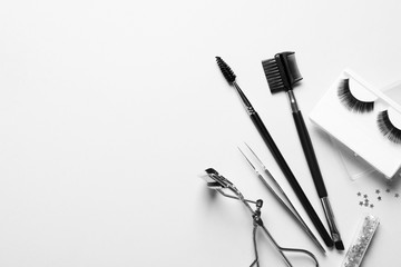 Composition with false eyelashes and tools on white background, top view