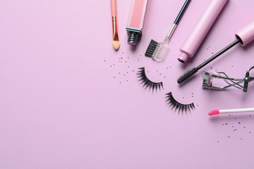 Flat lay composition with false eyelashes and other makeup products on pink background, space for...