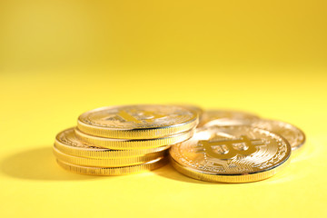 Shiny bitcoins on yellow background. Digital currency
