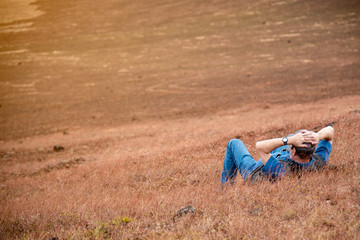 The man relaxing on outdoor. Lying down in sawanna area. Feeling relaxing.