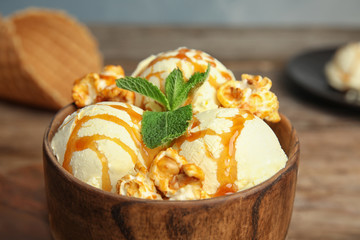 Delicious ice cream with caramel popcorn and sauce served on table, closeup