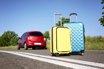 Color suitcases near family car on highway. Summer vacation
