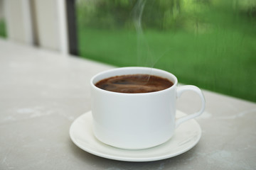Cup of hot aromatic coffee on white wooden windowsill. Rainy weather