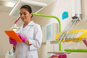 Concentrated female dentist standing with an orange tablet