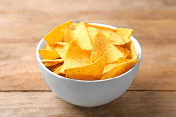 Tasty mexican nachos chips in bowl on wooden table