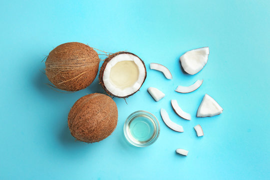 Flat lay composition with ripe coconuts and natural organic oil on blue background