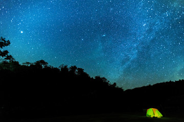 Tourist summer camping at night on the  mountain.A tent glows under a night sky full of stars. A wonderful night.