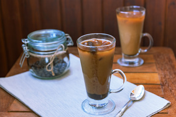 Two glasses of iced coffee on wooden table, soft focus