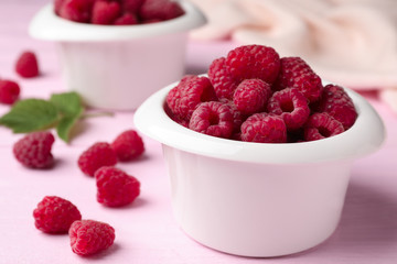 Bowl of delicious fresh ripe raspberries on pink wooden table, closeup view. Space for text