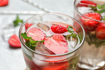 Fototapeta na wymiar Glass of refreshing drink with strawberry and mint on table, closeup view