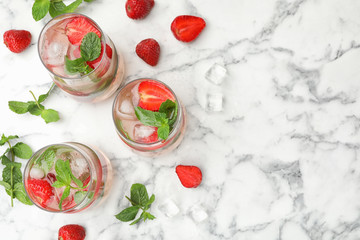 Glasses of refreshing drink with strawberry and mint on marble table, flat lay. Space for text