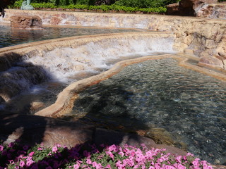 Wide view of of water cascading from a waterfalls in a landscaped garden