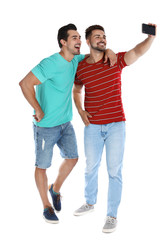 Fototapeta premium Happy young men taking selfie on white background
