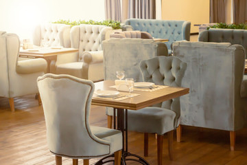 The interior design of the restaurant and a table with wine glasses for two in daylight.