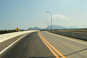 Open road on the bridge with mountain and blue sky in background, Southeast Asia, Thailand