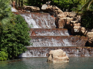 Water cascades down a man-made waterfalls in a landscaped garden