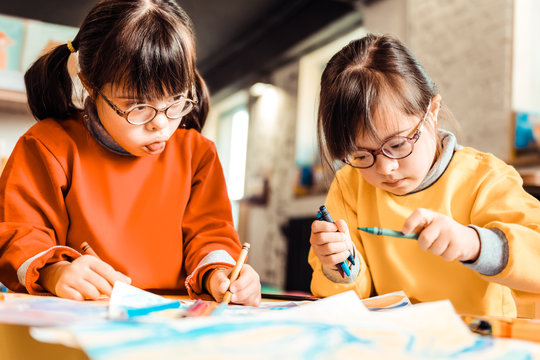 Little concentrated kids with down syndrome working on a new picture