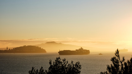 Fototapeta na wymiar Cargo ship is going in Auckland harbour in sunrise