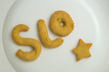 The letters of the English alphabet SLO and an asterisk made of shortcrust dough, lie on a white plate.