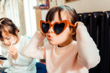 Expressive young lady trying on heart shaped sunglasses