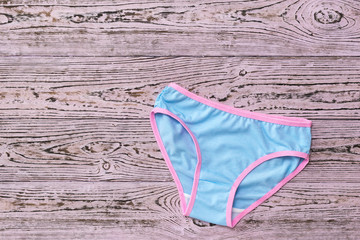 Women's panties are blue with a pink stripe on a wooden background. Fashionable concept. Beautiful lingerie. The view from the top.
