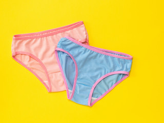 Blue and pink panties on yellow background. The concept of meeting lovers. Underwear. The view from the top.