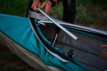 The process of assembling and repairing kayaks: metal skeleton, PVC skin, wooden and aluminum frames. Male hands assemble the canoes and paddle boating.