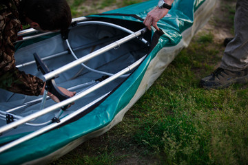 Obraz premium The process of assembling and repairing kayaks: metal skeleton, PVC skin, wooden and aluminum frames. Male hands assemble the canoes and paddle boating.