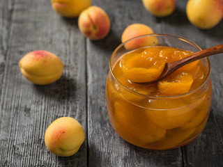 Naklejka na ściany i meble A jar of apricot jam on a black rustic table.