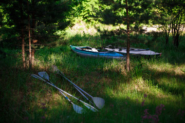 Two kayaks lie on the shore with oars. Preparing for water campaign, assembling kayak