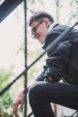 a young rebel in a jacket and jeans on the background of an old crumbling building with glasses and...