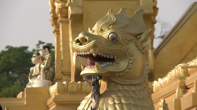 An extreme close up shot of the head of a golden chinthes in a temple in Myanmar