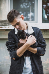 a young rebel in a jacket and jeans on the background of an old crumbling building with glasses and...
