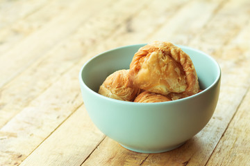 Curry puff pastry in cyan vintage bowl put on old table with copy-space