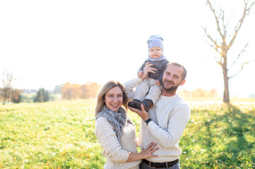 Happy family outdoor activity. Young emotional parents playing with their child in sunny day.