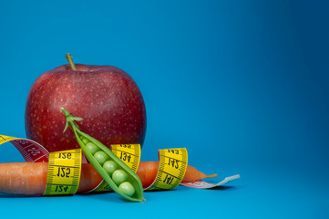 Measuring tape carrot and apple on blue background