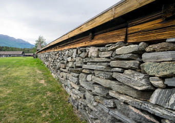 Stone wall that has wooden old looking roofing. It surrounds the famous stave church graveyard. Lom, Norway, Europe.