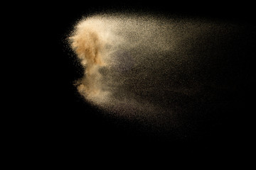 Abstract sand cloud.Golden colored sand splash agianst dark background.Yellow sand fly wave in the...