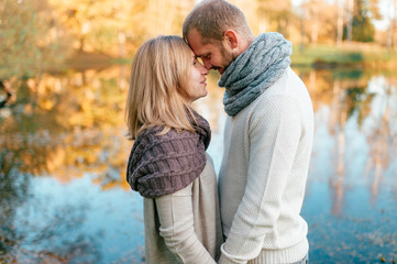 Fototapeta premium Loving couple in knitted clothes romantic portrait with reflected lake on background.