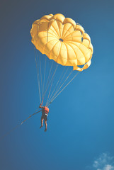 Skydiver on colorful parachute in sunny blue sky. Active lifestyle. Extreme sport.