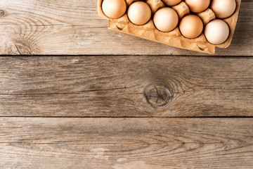 Overhead shot of chicken eggs in carton box on wooden table
