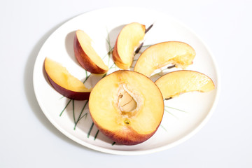 Slices of peach on a plate in a white background