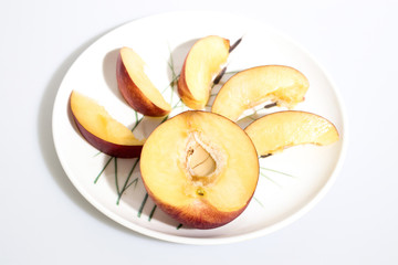 Naklejka na ściany i meble Slices of peach on a plate in a white background